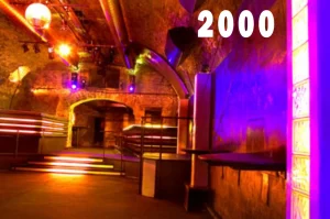Innenansicht des Eiskeller Clubs im Jahr 2000 mit orange-violett beleuchtetem Ziegelgewölbe, Spiegelkugel und erhöhtem Sitzbereich.